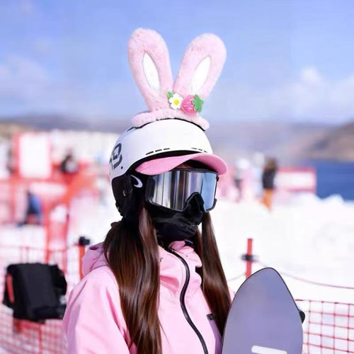 Person wearing a pink bunny helmet with rabbit ears on a snowy background