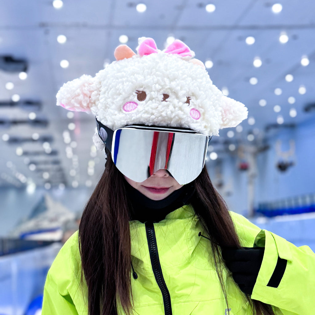 Person wearing a fluffy sheep-themed helmet and ski goggles in an indoor skiing facility.