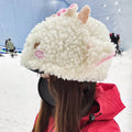 Person wearing a fluffy white helmet with pink accents in a snowy landscape