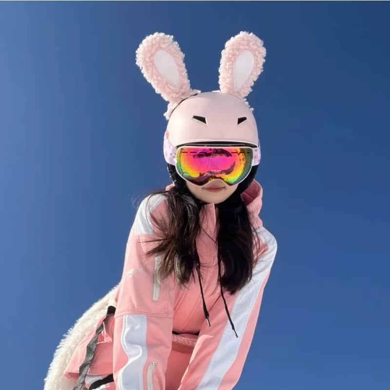 Person wearing a pink bunny helmet with goggles against a blue sky